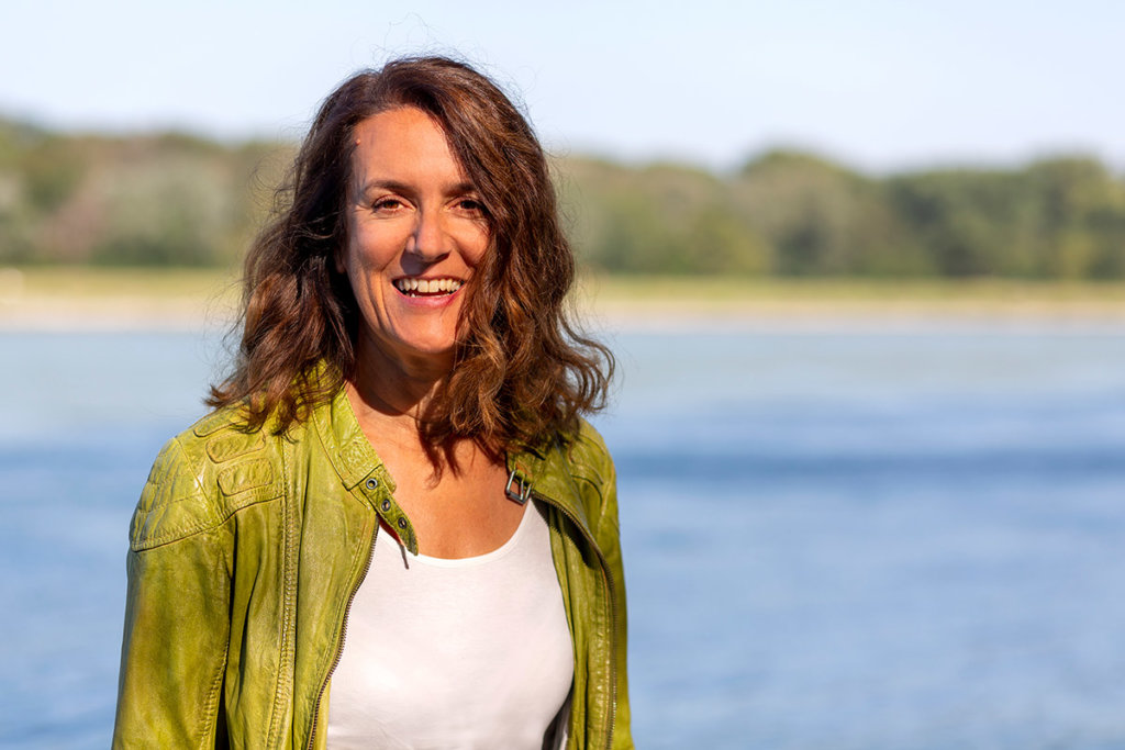 Begleiterinnen: Martina Gross im Portrait. Im Hintergrund ein Fluss und Bäume